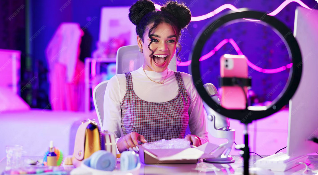 Screenshot 2025-10-09 at 11-55-37 Unboxing live stream and happy influencer woman with microphone neon light and makeup in home studio content creator beauty streamer or excited girl in online video for[...]