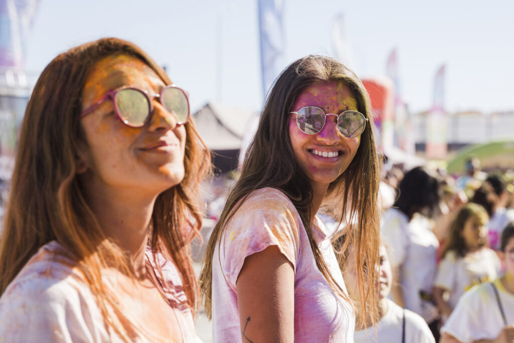 two-young-women-wearing-sunglasses-with-holi-powder-face